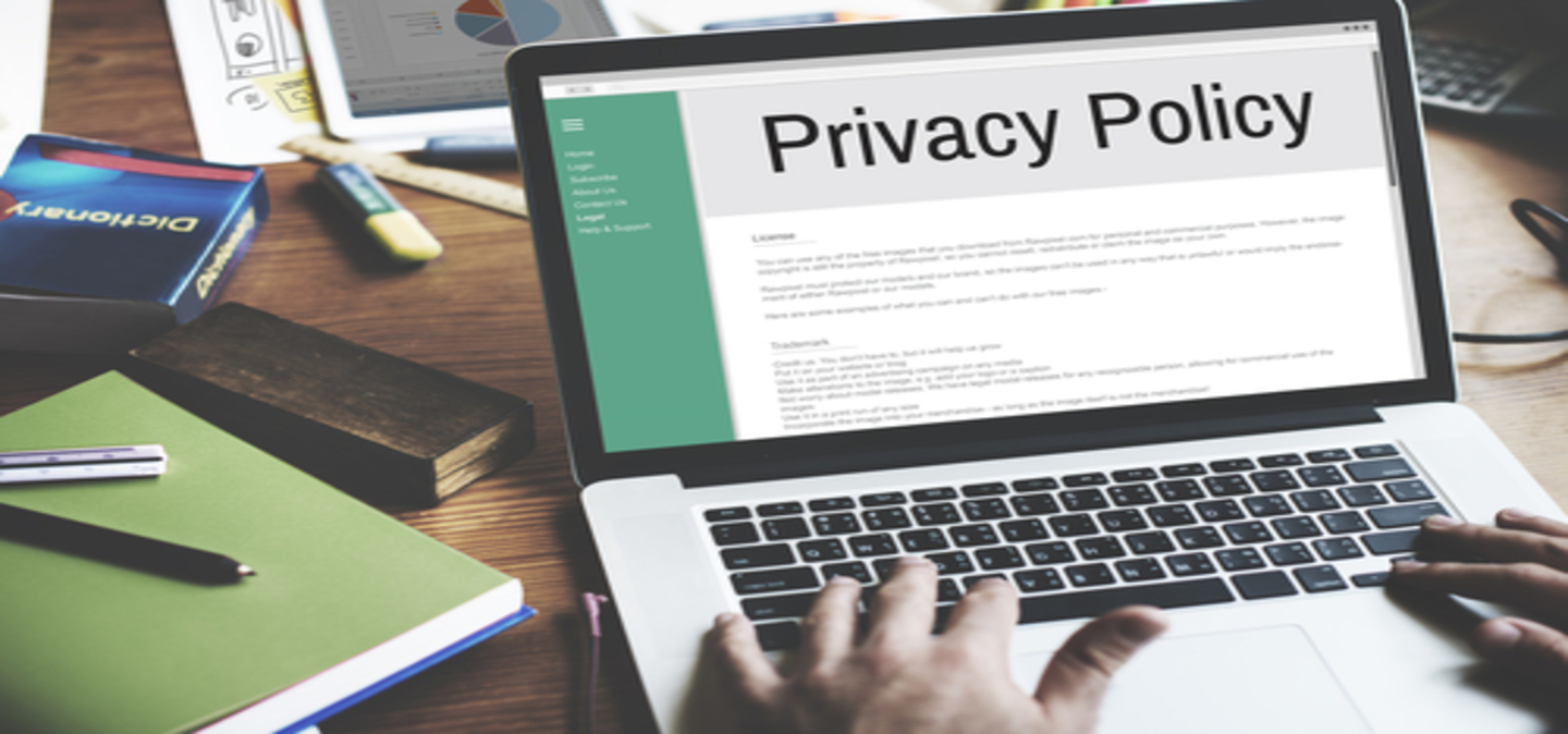 image of laptop on table and hands typing with screen showing a Privacy Policy